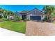 Charming home exterior featuring a well-manicured lawn, paver driveway, and a gray stucco facade with lush landscaping at 4607 Benito Ct, Bradenton, FL 34211
