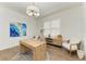 Bright and stylish office space with wood desk, chandelier, accent rug, and blue abstract wall art at 4607 Benito Ct, Bradenton, FL 34211