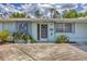 Close-up of the front door and adjacent windows of the light blue home with mature landscaping at 5602 Espanola Ave, North Port, FL 34287