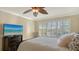 Bedroom showcases plantation shutters, ceiling fan and television with a bed accented by neutral colors and textured pillows at 5934 Guarino Dr, Sarasota, FL 34238