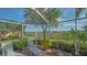 Enclosed lanai showcasing lounge chairs surrounded by lush landscaping with beautiful lake views at 5934 Guarino Dr, Sarasota, FL 34238