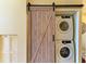 This laundry room features a stackable washer and dryer, and is accessible through a sliding wooden barn door at 7507 Preserves Ct # 7507, Sarasota, FL 34243