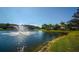 Scenic view of a pond with a fountain, surrounded by lush landscaping and residential buildings under a clear blue sky at 7685 Plantation Cir # B, University Park, FL 34201