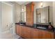 Bathroom vanity with dual sinks, dark countertops, light-toned cabinets and a toilet at 8058 Santa Cruz Dr, Port Charlotte, FL 33981
