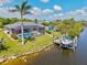 Aerial view of a single-story home featuring a screened-in pool and private dock on the canal at 8058 Santa Cruz Dr, Port Charlotte, FL 33981