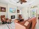 Bright living room features a leather sofa, fireplace, television, and stylish ceiling fan at 8058 Santa Cruz Dr, Port Charlotte, FL 33981