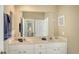 Bathroom featuring double sinks, a large mirror, white cabinetry, and neutral tones at 8222 Harborside Cir, Englewood, FL 34224
