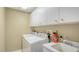 Laundry room featuring a washer, dryer, utility sink, overhead cabinets for storage, and tiled floor at 8222 Harborside Cir, Englewood, FL 34224