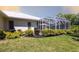 Landscaped backyard with well-maintained lawn, flowering bushes and screened-in patio, perfect for relaxing outdoors at 832 Carnoustie Dr, Venice, FL 34293