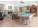 Open-concept living area with a pool table, fireplace, and lovely wood floors offers a comfortable living space at 832 Carnoustie Dr, Venice, FL 34293