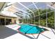 Backyard pool area with a spa, covered patio and lush landscaping, perfect for outdoor gatherings and relaxation at 832 Carnoustie Dr, Venice, FL 34293