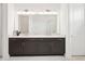 Bright bathroom features a double vanity with dark cabinets, a large mirror, and modern lighting at 8405 Golden Beach Ct, Parrish, FL 34219