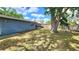 Lush backyard with a mature shade tree, a partially covered patio, and fenced boundary at 8731 Peggy Ave, Sarasota, FL 34231
