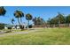 Backyard with lush grass, a tennis court, picnic tables, a sidewalk and tropical palms at 8731 Peggy Ave, Sarasota, FL 34231