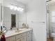 Well-lit bathroom featuring a large mirror, vanity with sink, and a separate toilet area at 10616 Ayear Rd, Port Charlotte, FL 33981