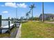 Dock with boat, palms, and tiki hut overlooking waterfront and lush landscaping at 10616 Ayear Rd, Port Charlotte, FL 33981