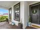 Charming covered front porch with plants and brown front door at 11435 Apple Tree Cir, Bradenton, FL 34211