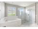 Elegant main bathroom with soaking tub, glass enclosed shower, and marble tile at 11435 Apple Tree Cir, Bradenton, FL 34211