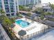 Aerial view of a sparkling pool area with lounge chairs and tiki umbrellas, surrounded by lush greenery and well-maintained grounds at 1212 Benjamin Franklin Dr # 708, Sarasota, FL 34236