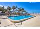 Resort-style pool provides relaxation surrounded by lush palm trees and tiki huts, all under a clear, blue sky at 1212 Benjamin Franklin Dr # 708, Sarasota, FL 34236