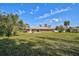 Spacious backyard with well-maintained lawn, palm trees, and a metal roof on the brick home at 12305 Harland St, North Port, FL 34287