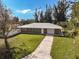 Charming brick home with a metal roof, long driveway, and a well-maintained front lawn at 12305 Harland St, North Port, FL 34287