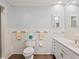 Bathroom with white tile walls, tile floor, a toilet, towel racks, and a sink at 1248 Northport Dr, Sarasota, FL 34242
