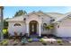 Home's elegant entrance featuring stately columns, a decorative glass door, and lush landscaping at 12628 Daisy Pl, Bradenton, FL 34212