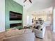 Open-concept living room featuring a decorative green accent wall, fireplace, and flows into a modern white kitchen at 12628 Daisy Pl, Bradenton, FL 34212