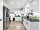 Well-lit kitchen featuring white cabinets, stainless steel appliances, and dark countertops at 1311 Cypress Ave, Venice, FL 34285