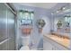 Well-lit bathroom with a glass shower, vanity with granite countertop, and decorative wall shelving at 1759 Lake Pl # 1759-B, Venice, FL 34293