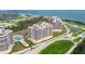 An aerial view showcases the condo buildings, pool, tennis courts, and waterfront at 3030 Grand Bay Blvd # 323, Longboat Key, FL 34228