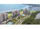 An aerial view shows luxurious condo buildings with tennis courts, a pool, and a marina at 3030 Grand Bay Blvd # 323, Longboat Key, FL 34228
