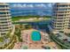 Aerial view of a community pool, hot tubs, putting green, and bay, nestled between luxurious high-rise buildings at 3030 Grand Bay Blvd # 323, Longboat Key, FL 34228