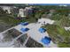 Aerial view showcasing a pristine beach area with shaded picnic pavilions, a volleyball court, and landscaping at 3030 Grand Bay Blvd # 323, Longboat Key, FL 34228