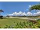 Scenic shot of lush golf course greenery, a distant sand trap and pond against a vibrant blue sky and cloudscape at 3030 Grand Bay Blvd # 323, Longboat Key, FL 34228
