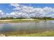 Picturesque golf course view with a serene pond, sandy hills, and clear skies filled with fluffy clouds at 3030 Grand Bay Blvd # 323, Longboat Key, FL 34228