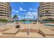 Community pool area with a large pool, lounge chairs, and umbrellas between matching high rise buildings at 3030 Grand Bay Blvd # 323, Longboat Key, FL 34228