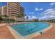 Large swimming pool surrounded by lounge chairs and palm trees with a view of the ocean and sky at 3030 Grand Bay Blvd # 323, Longboat Key, FL 34228