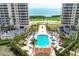 An aerial view shows the rectangular community pool surrounded by lounge chairs and palm trees, between two condo towers at 3030 Grand Bay Blvd # 323, Longboat Key, FL 34228