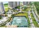 Aerial view of a tennis court with lush landscaping, located near high-rise condos and a paved road at 3030 Grand Bay Blvd # 323, Longboat Key, FL 34228