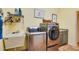 Well-lit laundry room boasts stainless steel washer, dryer, and utility sink with organized shelving at 361 Whitfield Ave, Sarasota, FL 34243