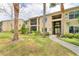 Tan condo building featuring tropical landscaping, screened patios, and well-maintained grassy areas at 4017 Crockers Lake Blvd # 1421, Sarasota, FL 34238