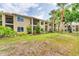 Multi-story tan building with lush landscaping featuring mature trees and green grass in the yard at 4017 Crockers Lake Blvd # 1421, Sarasota, FL 34238