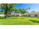 Expansive backyard featuring mature trees, lush green grass and exterior view of the house at 4172 Oakhurst W Cir, Sarasota, FL 34233