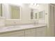 Bright bathroom featuring dual sinks, white cabinets, and a vanity with stylish mirrors and lighting at 4172 Oakhurst W Cir, Sarasota, FL 34233