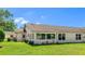 View of the home's rear exterior featuring a bright sunroom and manicured lawn at 4172 Oakhurst W Cir, Sarasota, FL 34233