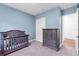 Cozy bedroom featuring a crib, closet, and gray dresser with soft, blue painted walls at 4308 Fly Rod Ter, Parrish, FL 34219