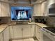 Galley kitchen with white cabinets, granite counters, and view to the dining and living areas at 4325 46Th W Ave # 202, Bradenton, FL 34210