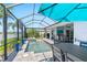 Enclosed pool and spa area with outdoor dining, summer kitchen, palm trees, and lake view at 4625 Foxtail Dr, Parrish, FL 34219